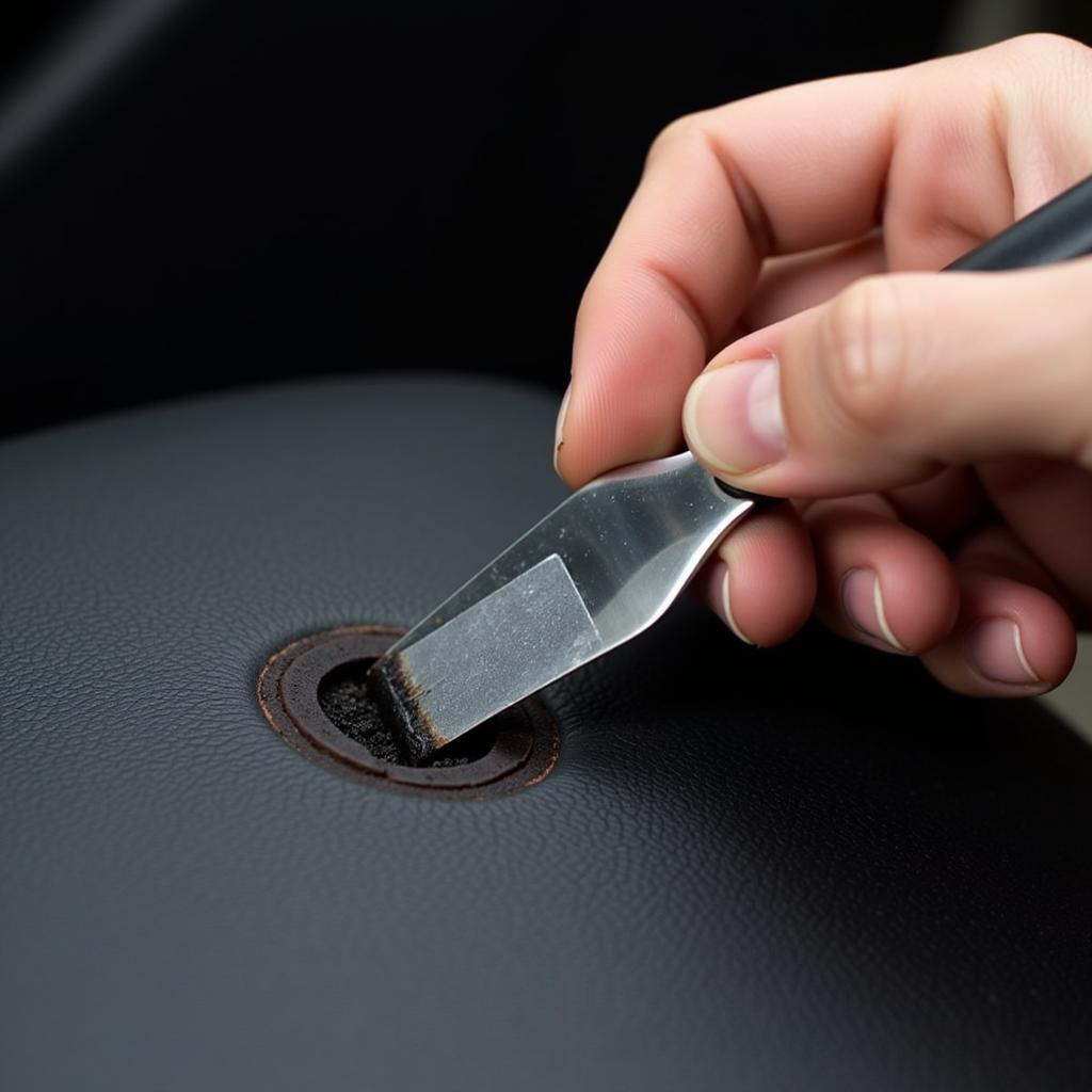 Applying leather filler to a cigarette burn on a car seat