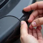 Close-up of a hand inspecting a car bumper scuff