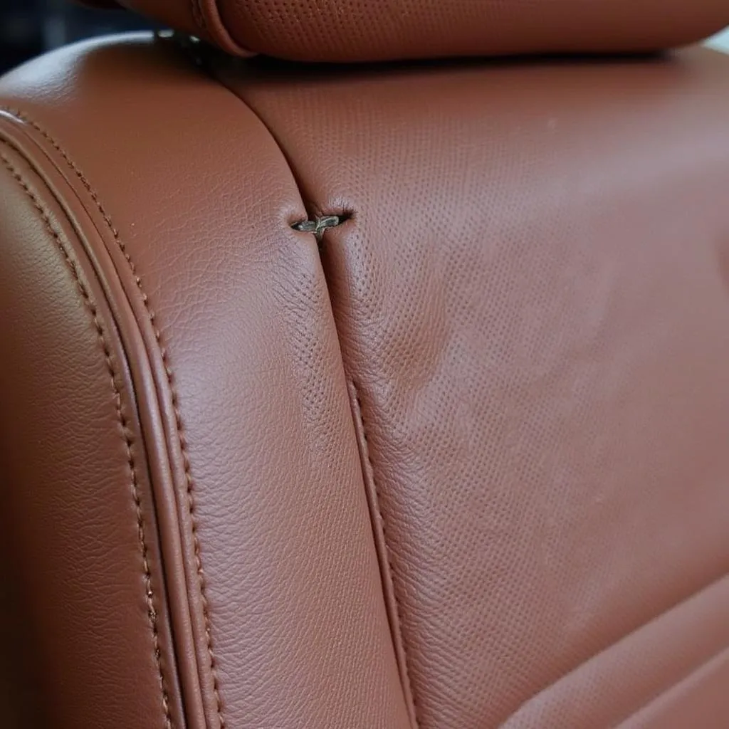 Close-up view of a small rip in a leather car seat