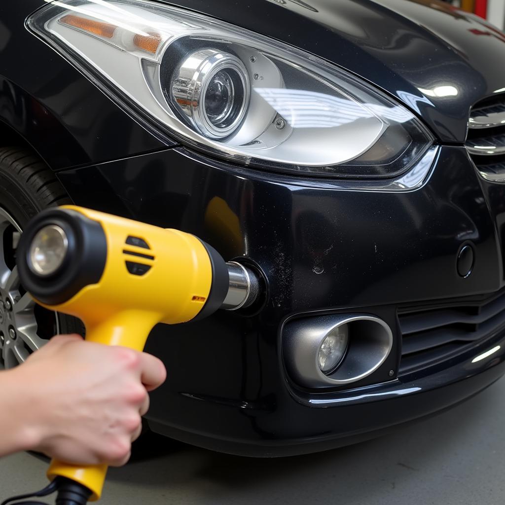 Applying heat to a scratched black plastic car bumper