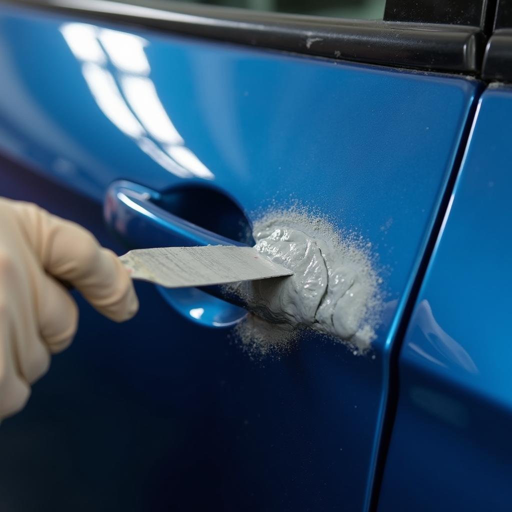 Applying car body repair paste to a dent