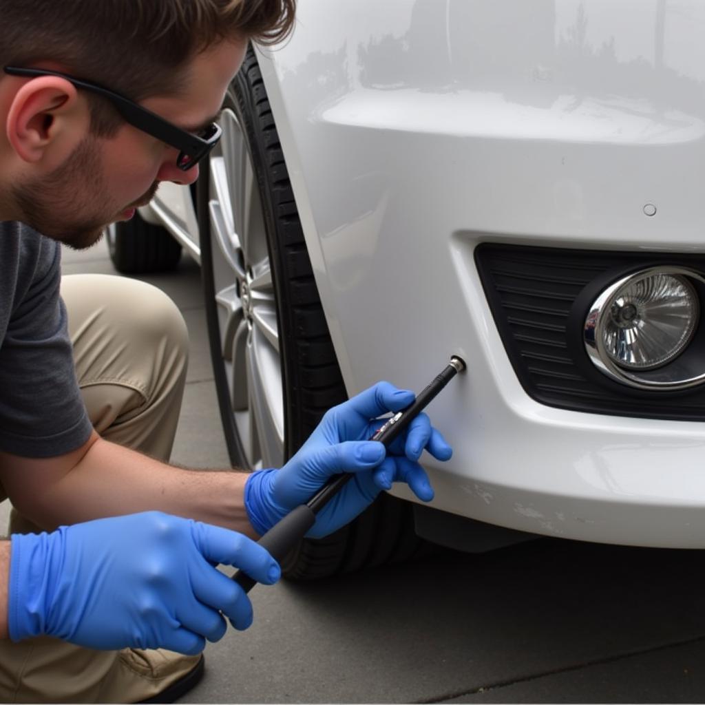 Close-up of the car bumper repair process using specialized tools and fillers.