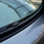 Damaged car window seal with visible cracks and gaps