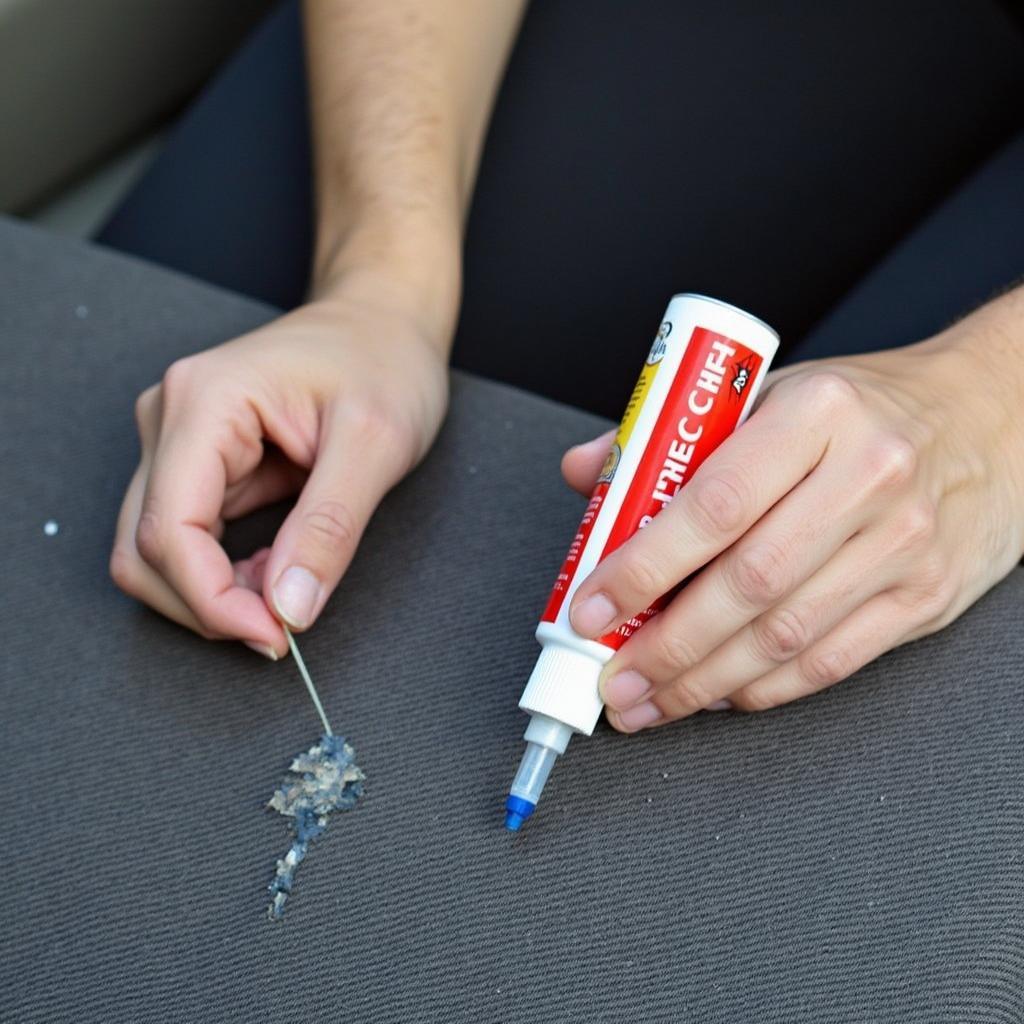 Repairing a tear in a fabric car seat with adhesive.