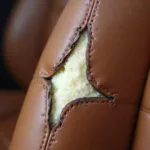 Close-up of a torn brown leather car seat