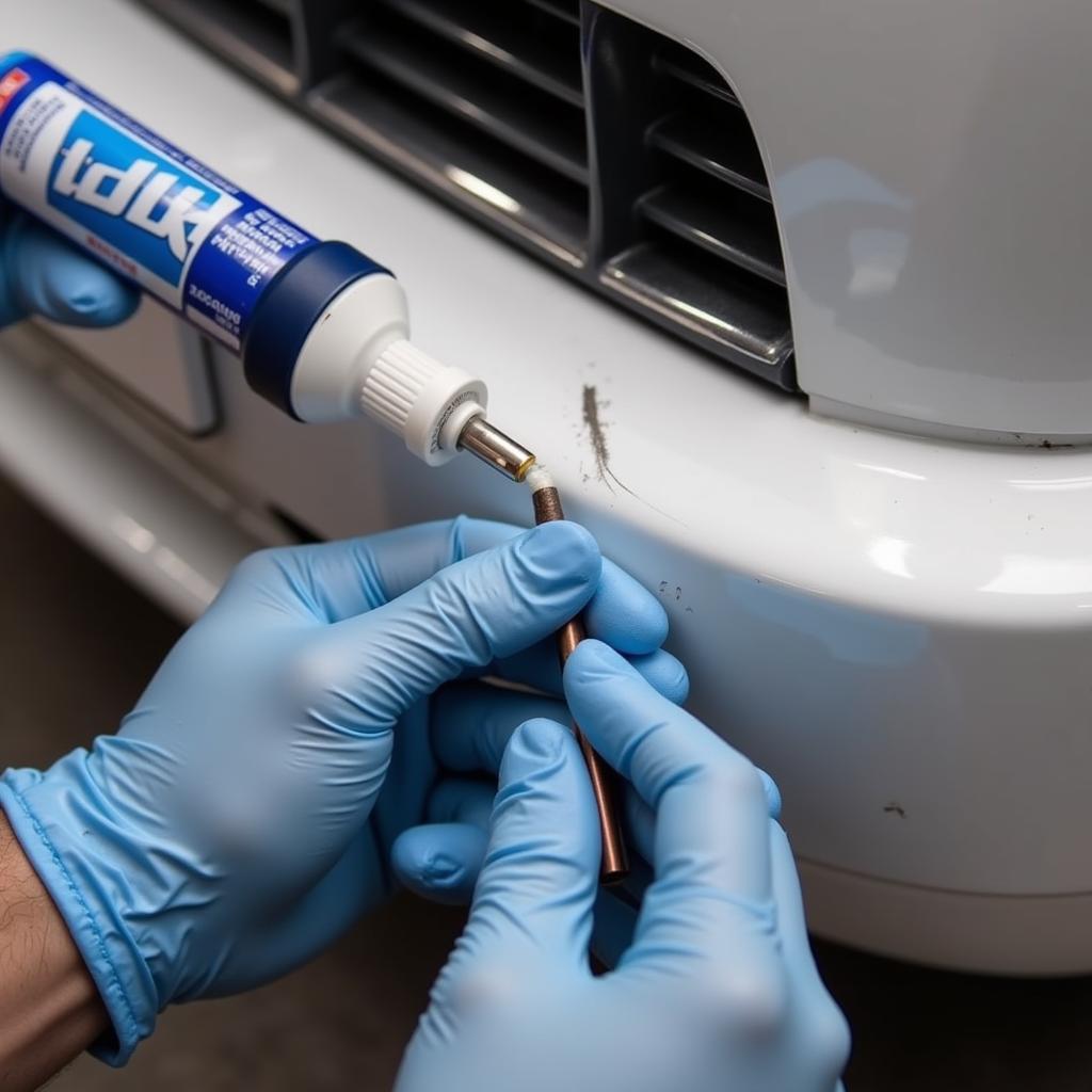 Applying filler from a plastic bumper repair kit to a dented bumper