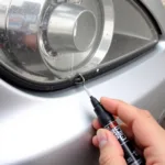 Applying touch-up paint to a car scratch using a paint pen