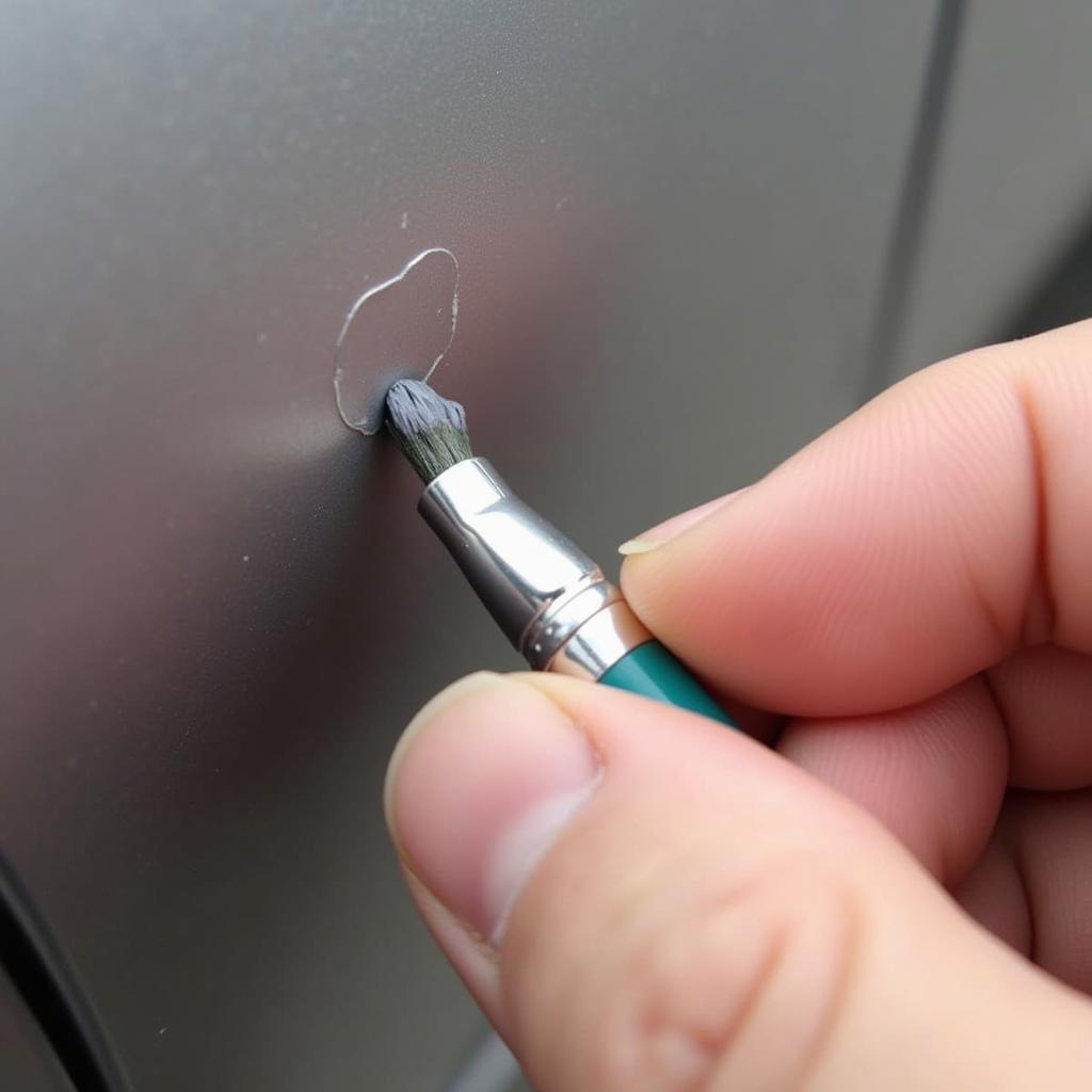 Applying touch-up paint to a car's paint chip using a fine-tipped brush.