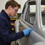 A student practices car body repair techniques in a Nottingham workshop