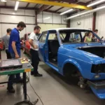 Students practicing car body repair techniques in a modern workshop