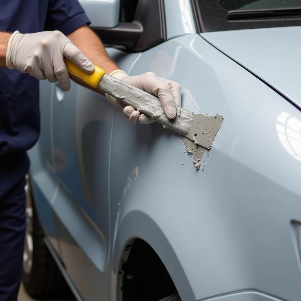 Applying car body repair filler to a damaged car panel