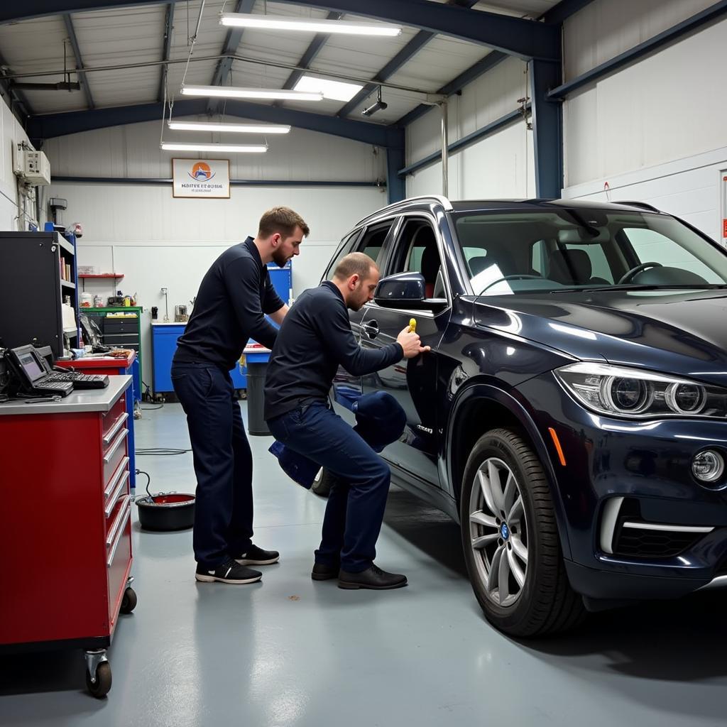 Car body repair shop in Tewkesbury with technicians working on a damaged vehicle.