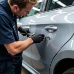 Car bodywork repair in Leeds: Dent removal process on a silver sedan.