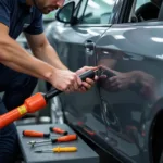 Car bodywork repairs in Swindon, showing a technician performing dent removal on a damaged vehicle.