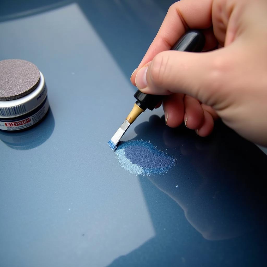 Repairing a paint chip on a car bonnet using touch-up paint and sandpaper.