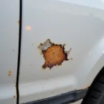 Chipped paint leading to rust formation on a car door