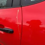 Deep paint scratch on a car door needing repair