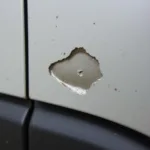 Close-up of a half-inch paint chip on a car door