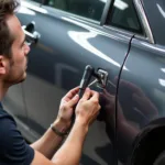 Technician performing paintless dent repair on a car door in Lancaster, PA.