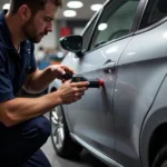 Peugeot 208 Dent Repair Process: A technician using specialized tools to remove a dent from a Peugeot 208's door panel, demonstrating the professional approach to car body repair.