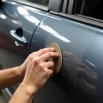 Repairing Paint Runs on a Car: Sanding a paint run on a car door to achieve a smooth finish.