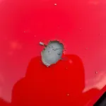 Close-up of rock chip damage on a red car hood