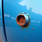 Close-up view of rust forming in a stone chip on car paint