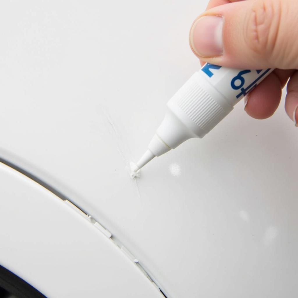 Applying a white gloss car paint repair pen to a car scratch